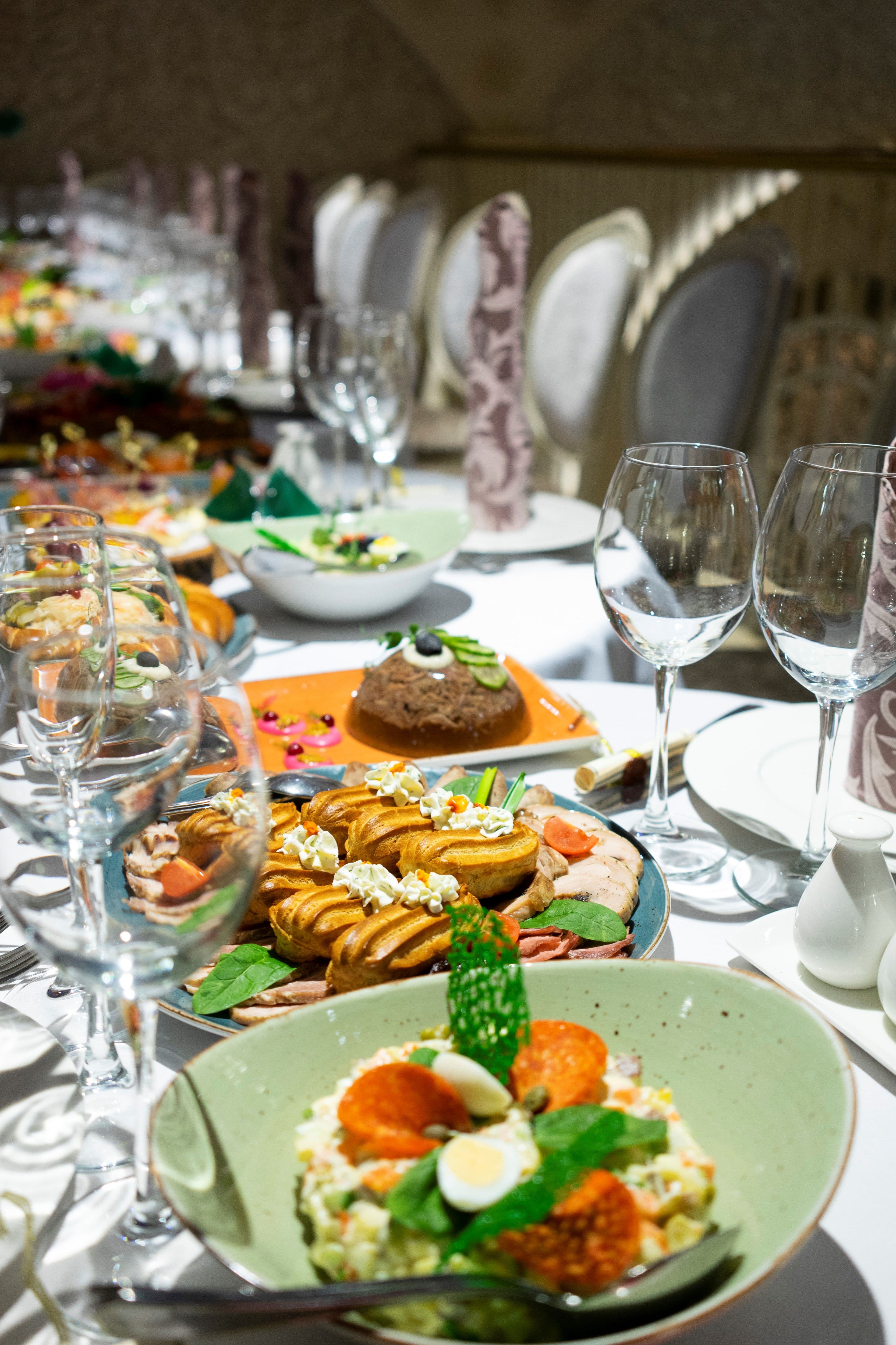 A long banquet table laid with plated starters, pastries and wine glasses